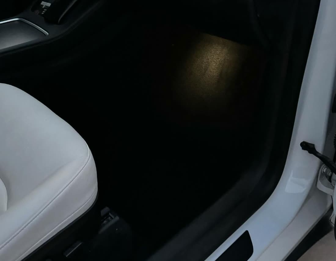 The same Tesla footwell after a full interior detail, carpet and sill spotless