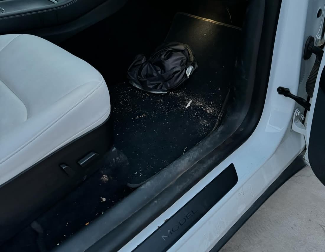 Tesla Model Y driver footwell before cleaning, debris across the carpet and sill